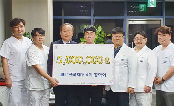 정영복 단국치대 4기 장학회장(사진 왼쪽에서 세 번째)이 본과 2학년 학생에게 장학금을 전달하고 있다.<단국치대 4기 장학회 제공>
