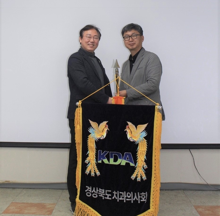 전용현 경북지부 신임 회장(사진 오른쪽)이 양성일 전임 회장으로부터 경상북도치과의사회기를 전달받고 있다<경북지부 제공>